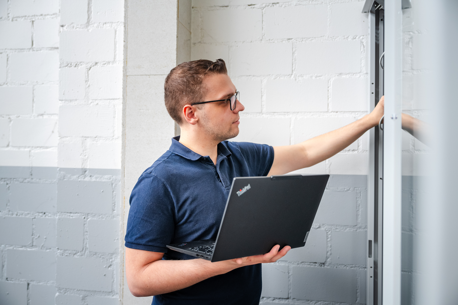 Serverschrank mit Mitarbeiter IT-Techniker der Brogli Informatik prüft einen Serverschrank beim Kunden vor Ort